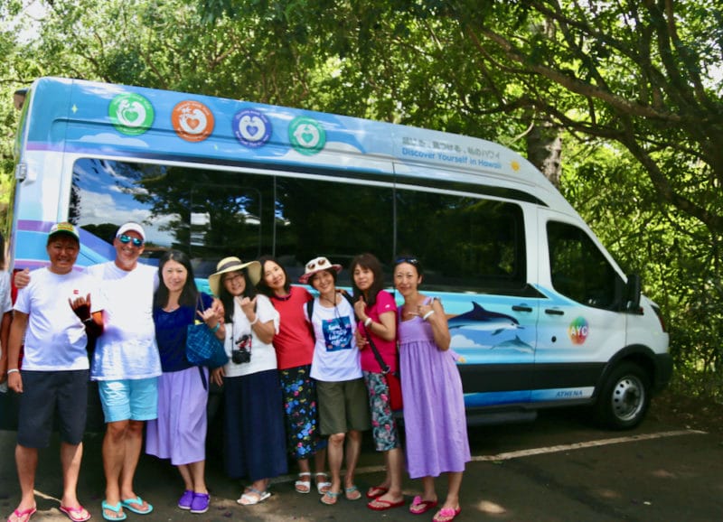 Group of people by the side of dolphin and you tour bus